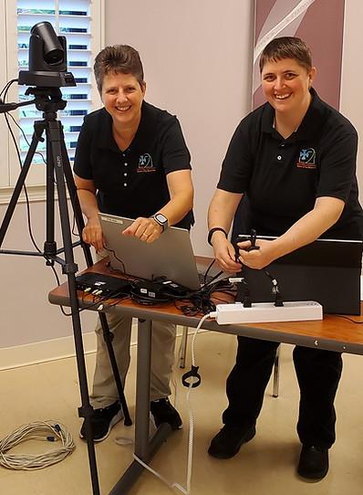 Sr. Michelle Sinkhorn, left, and Sr. Tamra Thomas set up equipment for a conference handled by Benedictine Tech Ministries. (Courtesy of Benedictine Tech Ministries)