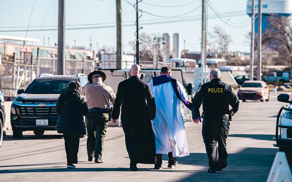 Scalabrinian Fr. Leandro Fossá, pastor of Our Lady of Mount Carmel Parish (right); Clarentian Fr. Paul Keller, missionary priest and provincial leader (center); and Sr. Alicia Gutierrez, a member of the congregation of the Society of Helpers (left) walk toward the ICE Broadview detention center escorted by two officers on Feb. 18, 2026. (Courtesy of Coalition for Spiritual and Public Leadership/Derek Carter)