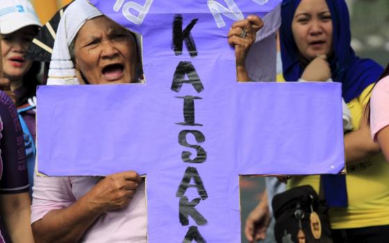 An activist holding a placard shouts anti-government slogans while protesting outside the presidential palace in Manila on March 8, 2016. In a statement on July 17, 2022, the religious superiors in the Philippines said "red-tagging" would not deter them f