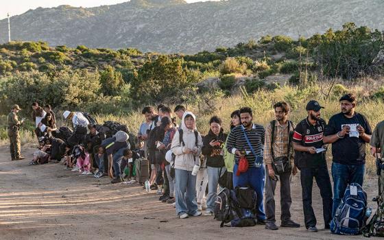 Asylum-seeking migrants stand in line to be transported at a staging area near the border wall in Jacumba Hot Springs, California, June 5, after U.S. President Joe Biden announced a sweeping border security enforcement effort. (OSV News/Reuters/Go Nakamura)