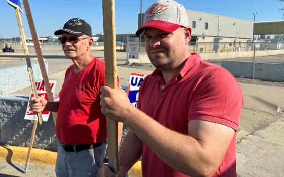 Striking United Auto Workers member Chris Jedrzejek, right, and his father picket outside Ford Motor Co.'s Michigan Assembly Plant Monday, Oct. 2, 2023, in Wayne, Mich.