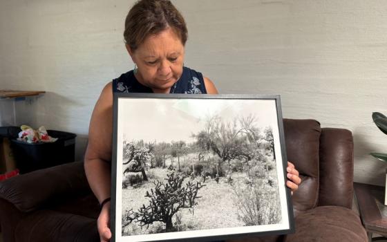 Dora Rodriguez looks at a black and white image of the crosses that mark the site in the Organ Pipe Cactus National Monument where 13 other people in the group she was traveling with died 45 years ago after they were abandoned in southern Arizona's sweltering July heat. (Anita Snow)