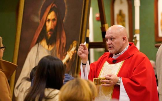 Father Carlos Martins, a member of the Companions of the Cross religious community, distributes Communion during a special Mass celebrated in honor of St. Jude the Apostle at St. Jude Church in Mastic Beach, N.Y., Nov. 27, 2023. Father Martins, a well-known exorcist and co-host of "The Exorcist Files" podcast, has been cleared of charges stemming from a relic exposition held in November 2024 at a parish in Joliet, Ill. (OSV News/Gregory A. Shemitz)