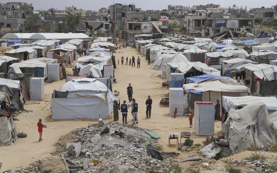 Catholic Relief Services workers talk with people at a tent camp for displaced Palestinians in Gaza May 5, 2025. (OSV News/CRS Staff)