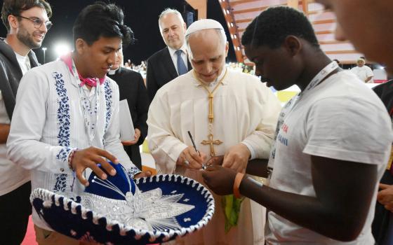Pope Leo XIV signs his name for a young man after presiding over a prayer vigil with hundreds of thousands of young people in Rome's Tor Vergata neighborhood Aug. 2, 2025. (CNS/Vatican Media)
