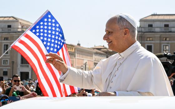 With a U.S. flag in the background, Pope Leo XIV waves to the crowd from the popemobile as he rides around St. Peter's Square at the Vatican before his weekly general audience Aug. 6, 2025. (CNS/Vatican Media)