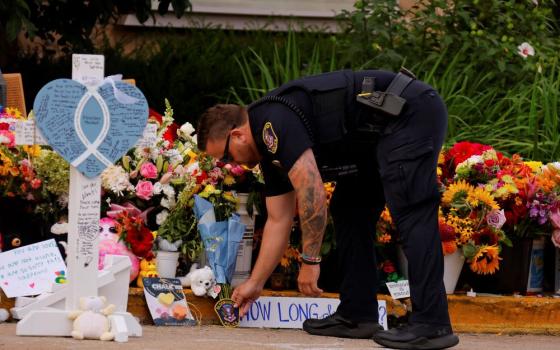  A police officer places a patch at a makeshift memorial at Annunciation Catholic Church after the Aug. 27 fatal shooting at the school Aug. 29 in Minneapolis. (AP/Bruce Kluckhohn)
