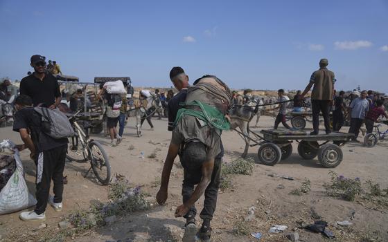 A Palestinian carries the body of a man killed while trying to receive aid near a distribution center operated by the U.S.-backed Gaza Humanitarian Foundation (GHF) in Netzarim, in the Gaza Strip, Aug. 4, 2025. (AP Photo/Abdel Kareem Hana)