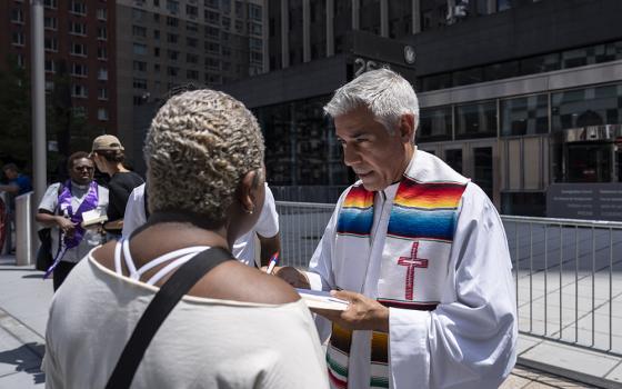 Fr. Fabián Arias, right, assists an immigrant family outside the Jacob K. Javits federal building, July 17, 2025, in New York. (AP/Yuki Iwamura)