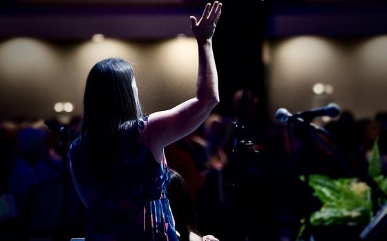 Julie Tragon, liturgist for the LCWR assembly, raises her hand in praise as CeCe Winans' song "Goodness of God" plays Aug. 15. (GSR photo/Dan Stockman)