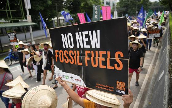 A protester holds a slogan as they join the global march to end fossil fuel on Sept. 15, 2023, in Quezon City, Philippines. (AP photo/Aaron Favila)