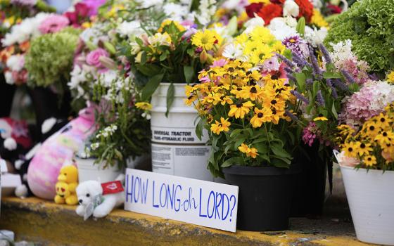 A sign stands amid flowers at a memorial at Annunciation Catholic Church after a school shooting Aug. 28, 2025, in Minneapolis. (AP/Abbie Parr)