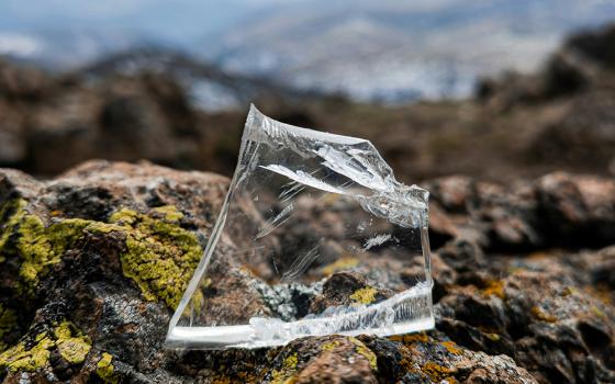 A piece of clear glass rests upon brown rock in this photo illustration. (Unsplash/Leutrim Fetahu)