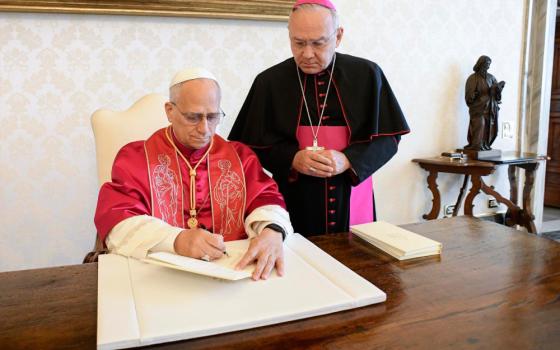 Pope Leo XIV signs his first apostolic exhortation, "Dilexi Te" ("I Have Loved You"), in the library of the Apostolic Palace at the Vatican Oct. 4, the feast of St. Francis of Assisi, as Archbishop Edgar Peña Parra, the substitute secretary for general affairs at the Vatican Secretariat of State, looks on. The exhortation was released Oct. 9. (OSV News/Reuters/Vatican Media)