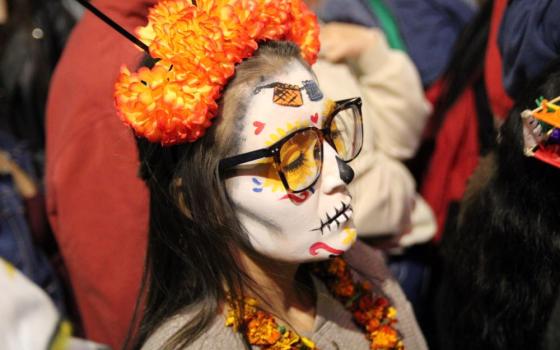 A woman dressed up as "La Catrina," a Mexican character also known as "The Elegant Death" watches the La Catrina parade in Mexico City Oct. 26.