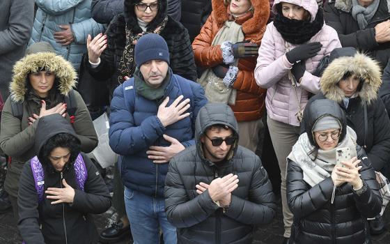 People gathered in St. Peter's Square at the Vatican for the recitation of the Angelus Jan. 7, 2024, the feast of the Baptism of the Lord, make the sign of the cross after Pope Francis asked them to do so in remembrance of having been baptized in the name of the Father, the Son and the Holy Spirit. (CNS/Vatican Media)