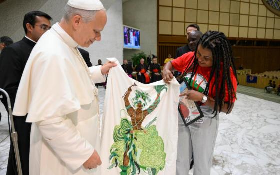 Pope Leo XIV holds a decorated piece of textile during a gathering of popular movements as part of their Jubilee in the Paul VI Audience Hall at the Vatican Oct. 23, 2025. (CNS/Vatican Media)