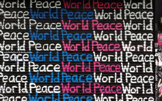 Graffiti with the words "World Peace" repeatedly written in white, blue and pink on a black background.