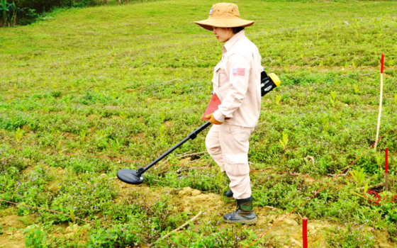 A female deminer carries out a search for unexploded ordnance in an abandoned garden in Cam Lo, Quang Tri province, Vietnam, on Aug. 28. (NCR photo) 