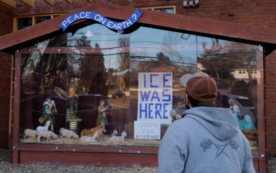 A sign reading "ICE Was Here" stands in the outdoor Nativity at St. Susanna Catholic Church in Dedham, Mass.