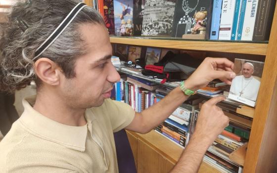 Ahmad Muna, assistant manager of the Educational Bookshop in east Jerusalem, points to a photo of the late Pope Francis he gave a place of honor at the shop. Muna, a non-observant secular Muslim, says Francis deserves a place of honor because of his commitment to Palestinian dignity. (NCR photo/Chris Herlinger)