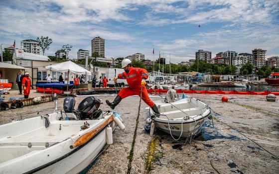 An expert works to clear a mass of marine mucilage, a thick, slimy substance made up of compounds released by marine organisms, from Turkey's Sea of Marmara at the Caddebostan shore, on the Asian side of Istanbul, June 8, 2021. (AP/Kemal Aslan)