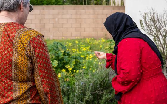 A woman staying in the CSJ Shelter for Refugee Families, a ministry that sponsors and houses families in the immigration process, shows St. Joseph Sr. Sue Dunning, left, the plants in the shelter's garden. (Courtesy of the Sisters of St. Joseph of Orange)