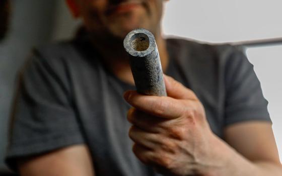 Troy Hernandez, an environmental justice activist with Pilsen Environmental Rights and Reform Organization shows a piece of lead pipe obtained from his residence during his home renovation, April 9, 2021, in Chicago's Pilsen neighborhood. (AP/Shafkat Anowar)
