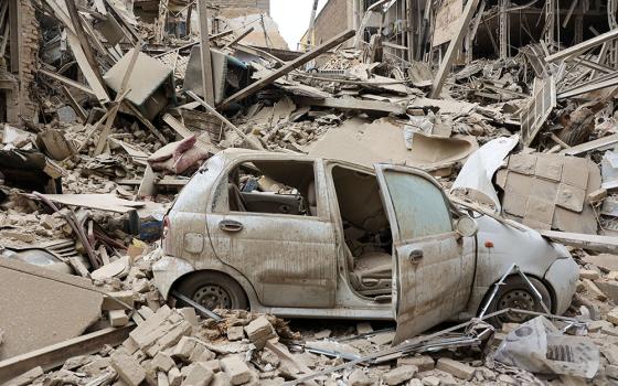 A destroyed vehicle is seen amid rubble at the site of a strike on a residential building in Tehran, Iran, March 16, 2026, amid the U.S.-Israeli war with Iran. (OSV News/WANA via Reuters/Majid Asgaripour)