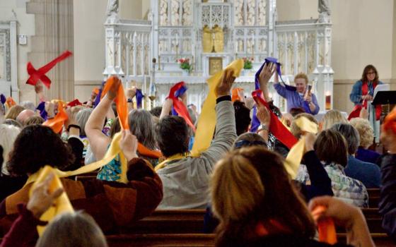 Attendees at the Women's Ordination Conference's 50th anniversary celebration wave multi-colored stoles May 22 in Detroit. (GSR photo/Dan Stockman)