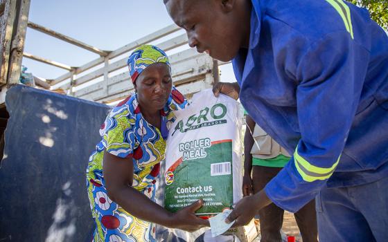 A community member receives food after redeeming her voucher at a distribution center in the village of Masera, Zimbabwe, Dec. 2, 2024. (OSV News/Catholic Relief Services/Dooshima Tsee)