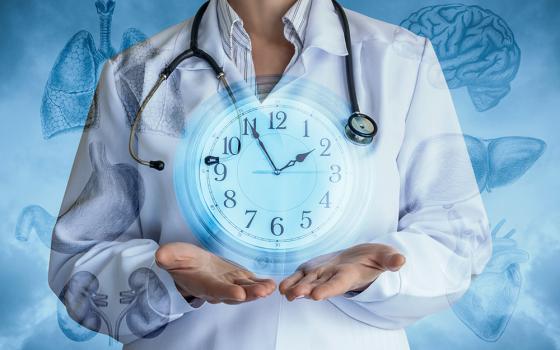 Composite image of a doctor with a clock and drawings of internal organs (Dreamstime/Nataliia Mysik)
