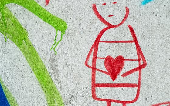 In a drawing illustration, a person with a blank expression cradles a heart. The drawing is done in red, with the heart colored in. Lines of green and blue are also visible against a white background. (Unsplash/Eduardo Goody)