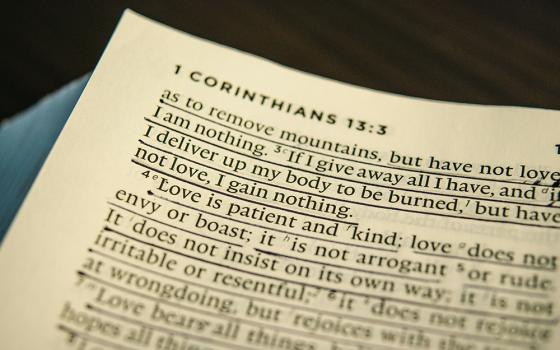 A photo illustration display the top left corner of a Bible, listing "1 Corinthians 13:3" at the top, with about ten lines of verses underneath. (Unsplash/Jonathan Meyer)
